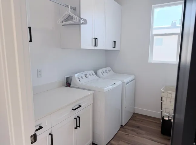 White cabinetry with black hardware, white countertop, wood-finish flooring, and a window