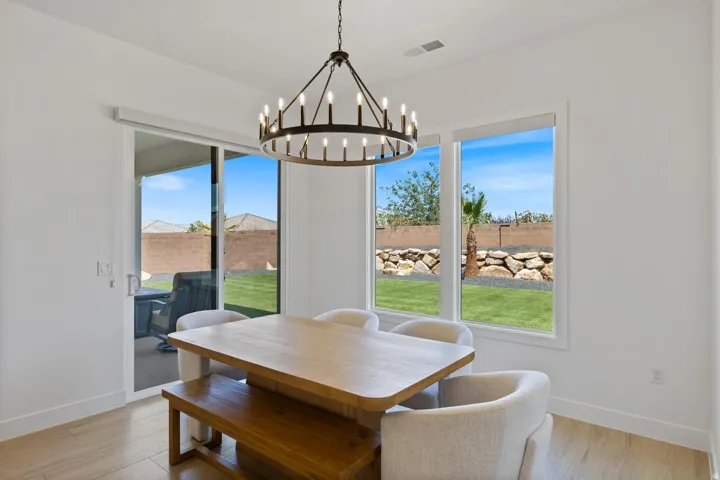 Spacious dining area featuring a contemporary chandelier, two large windows, a sliding glass door, and light wood-finish flooring