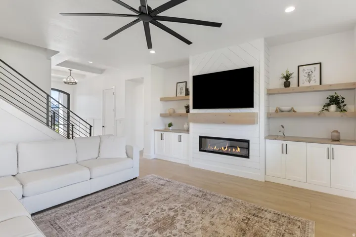 Light wood-finish flooring, linear electric fireplace, and built-in cabinetry with wood-tone countertops