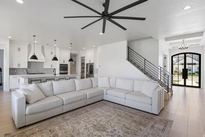 Open-concept living space featuring a sectional layout anchored by light-finish wood flooring and a large area rug