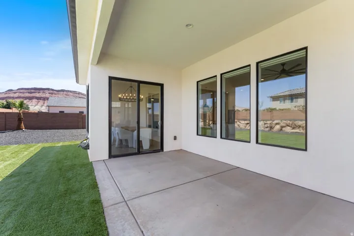 Expansive concrete patio with a covered outdoor area, complemented by a manicured artificial turf lawn