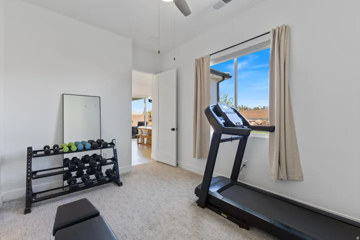 Carpeted room with a ceiling fan, a window with exterior visibility, and a door opening to an adjacent room