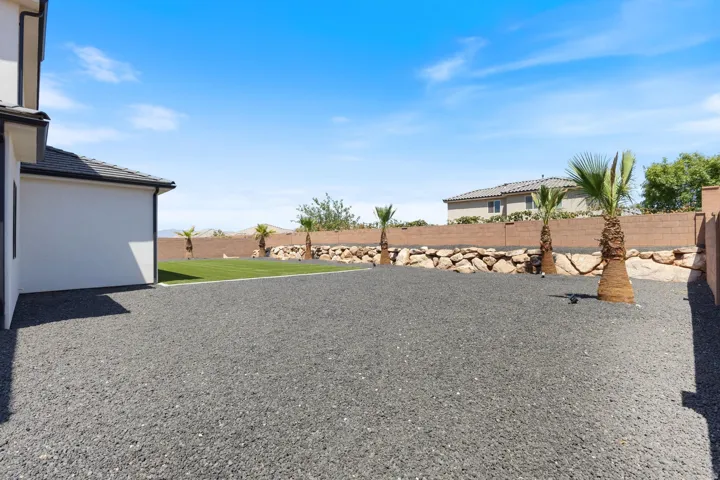 Expansive outdoor space featuring a large gravel area, manicured lawn, and mature palm trees