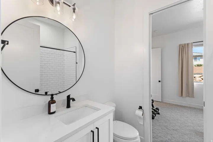 White vanity with integrated sink, black-finish faucet, and a circular framed mirror