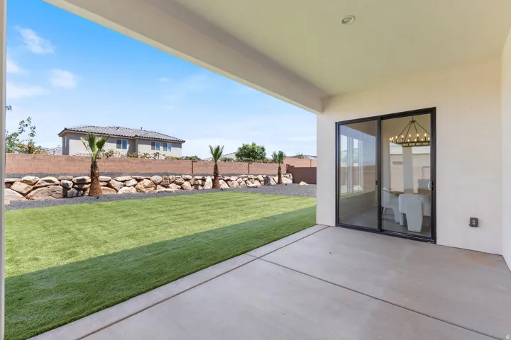 Expansive covered patio with polished concrete flooring overlooking a manicured lawn bordered by decorative stone landscaping