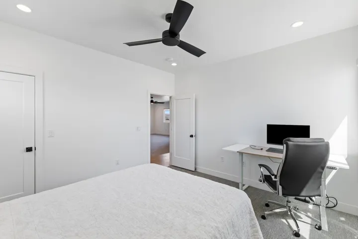 Bright secondary bedroom with recessed ceiling lighting, ceiling fan, and dedicated workspace featuring built-in desk with monitor setup