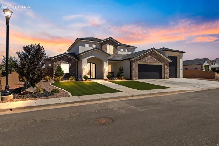 Stucco and brick exterior with a tiled roof, arched entryway, and dual garage doors