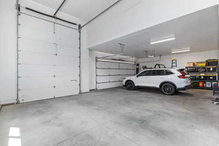 Spacious garage with multiple overhead doors, concrete flooring, and overhead lighting