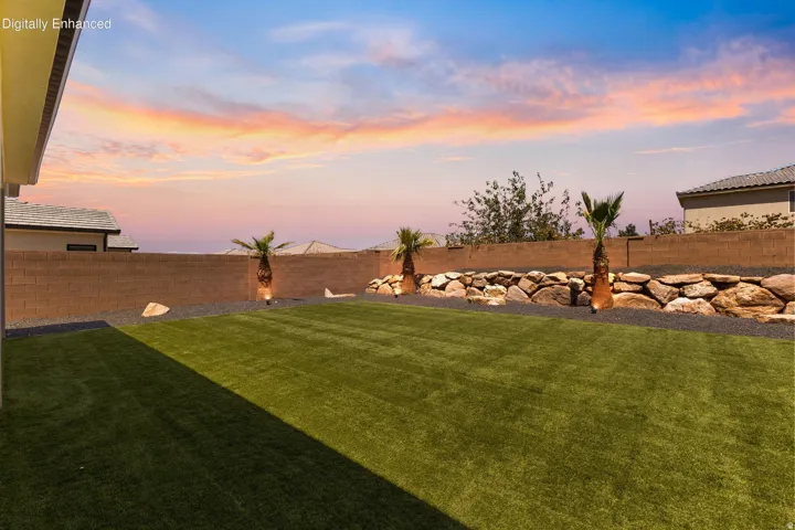 Expansive backyard with professionally manicured lawn, mature palm trees, and decorative rock landscaping