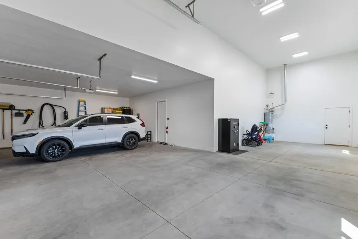 Spacious garage with concrete flooring, multiple overhead lighting fixtures, and high ceilings