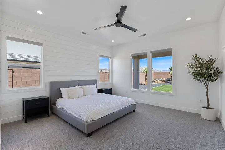 Recessed lighting, ceiling fan, shiplap accent wall, white walls, and multiple windows with outdoor views