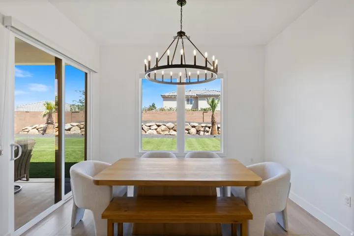 Matte black chandelier over a dining area with wood-finish flooring