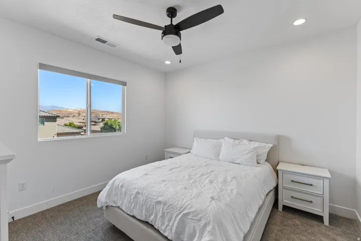 Recessed lighting with a ceiling fan, window with roller shade, and light gray carpeted flooring