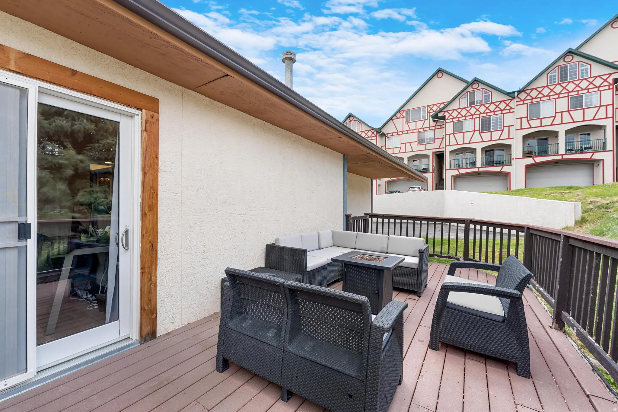 Expansive outdoor deck with composite decking, white stucco exterior, and a sliding glass door with wood trim