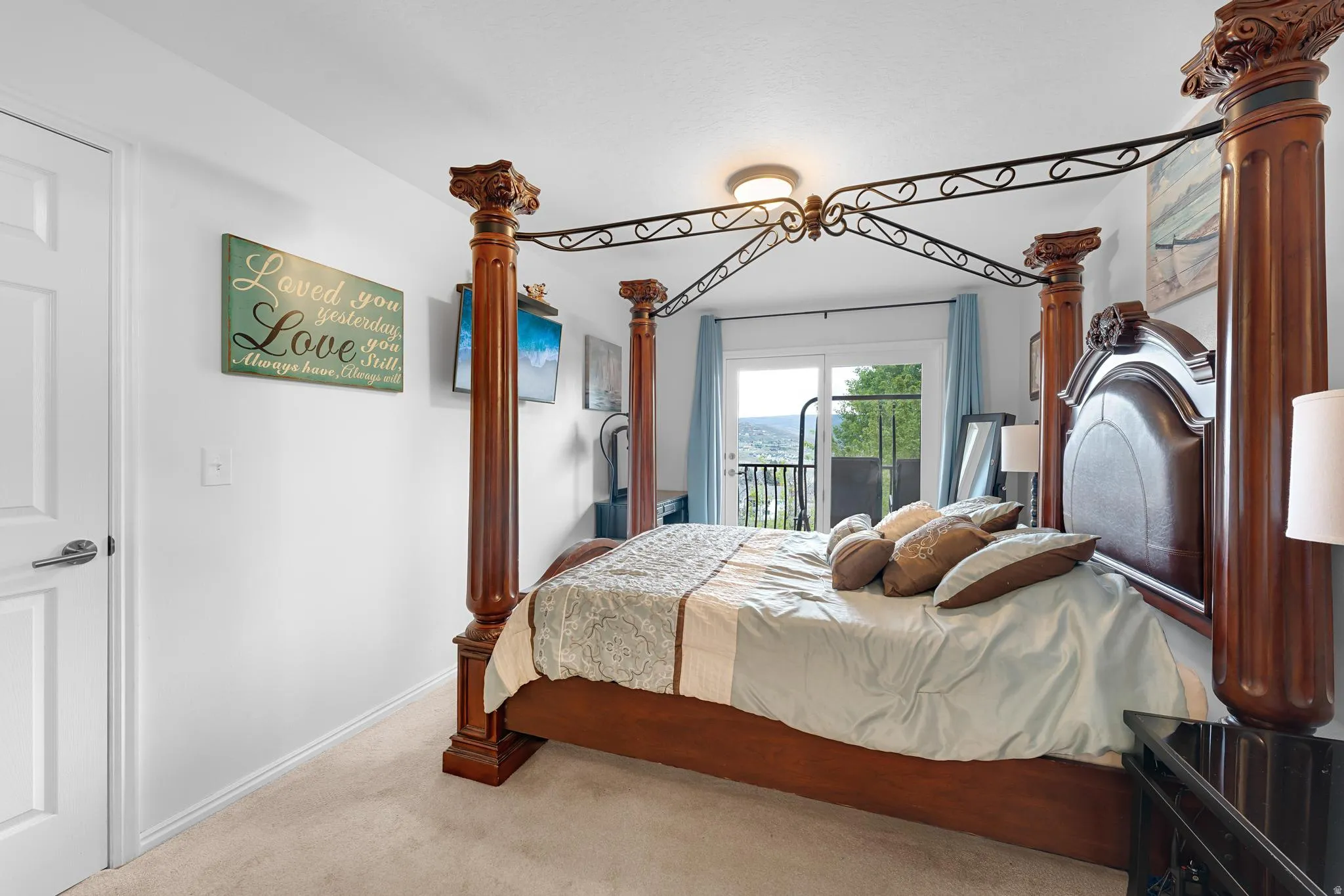 White walls with light-toned carpeting, featuring a sliding glass door opening to an outdoor balcony