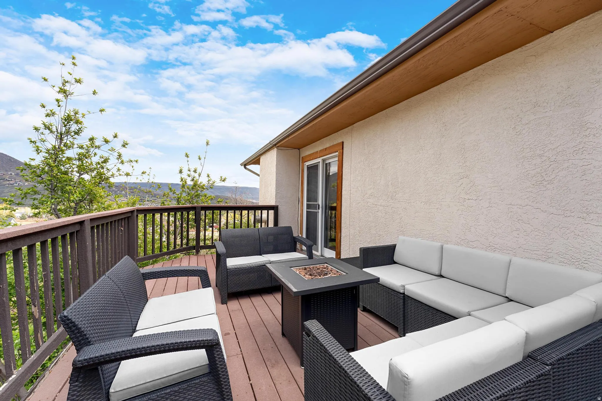 Outdoor deck with wood-finish flooring, stucco exterior, and sliding glass door access