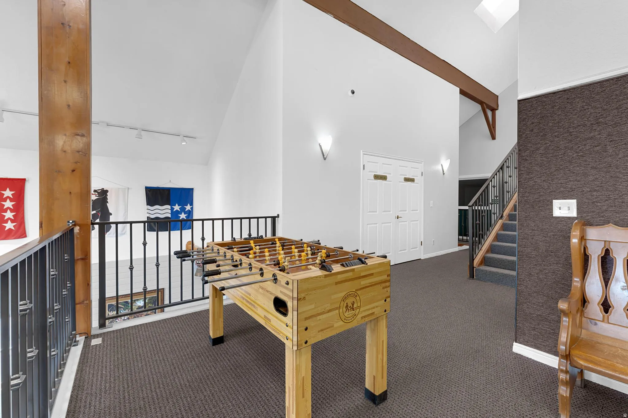 Upper-level landing featuring vaulted ceilings, a skylight, exposed wood beams, and carpeted flooring