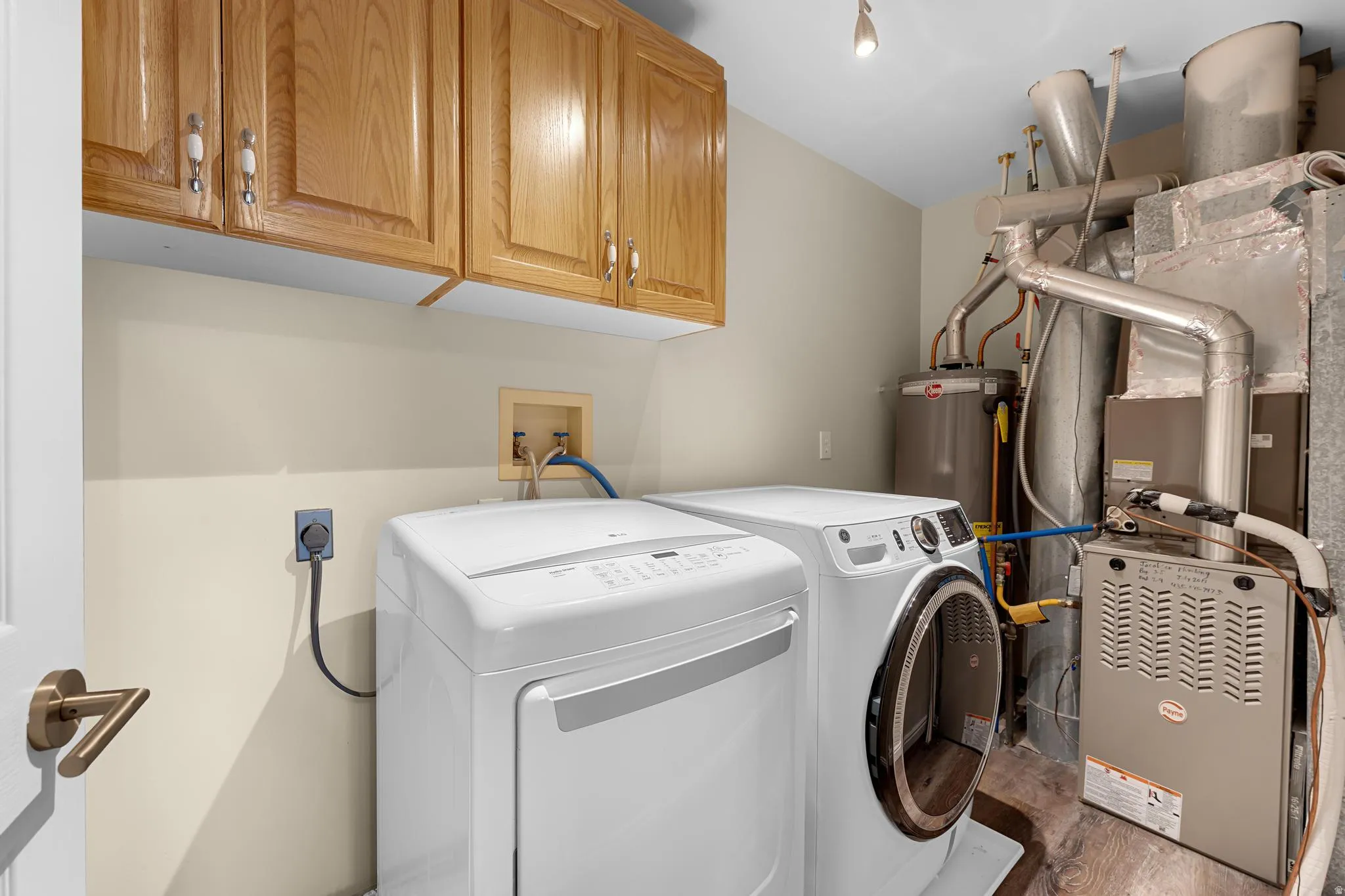 Wood-finish flooring, overhead cabinetry, and wall-mounted water heater