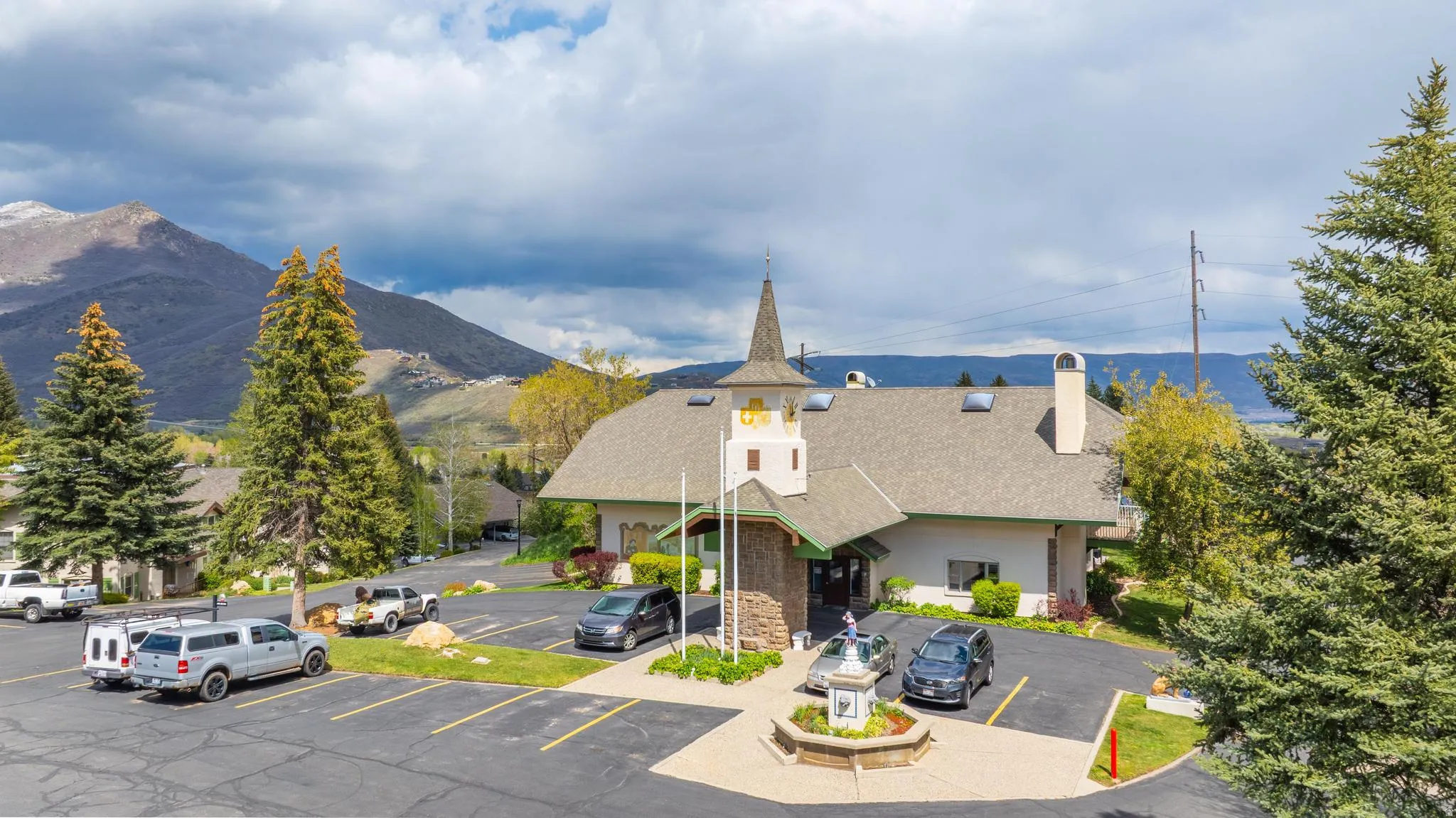 Property features a distinctive steeple, a circular driveway, an exterior fountain, a stone facade, and extensive parking