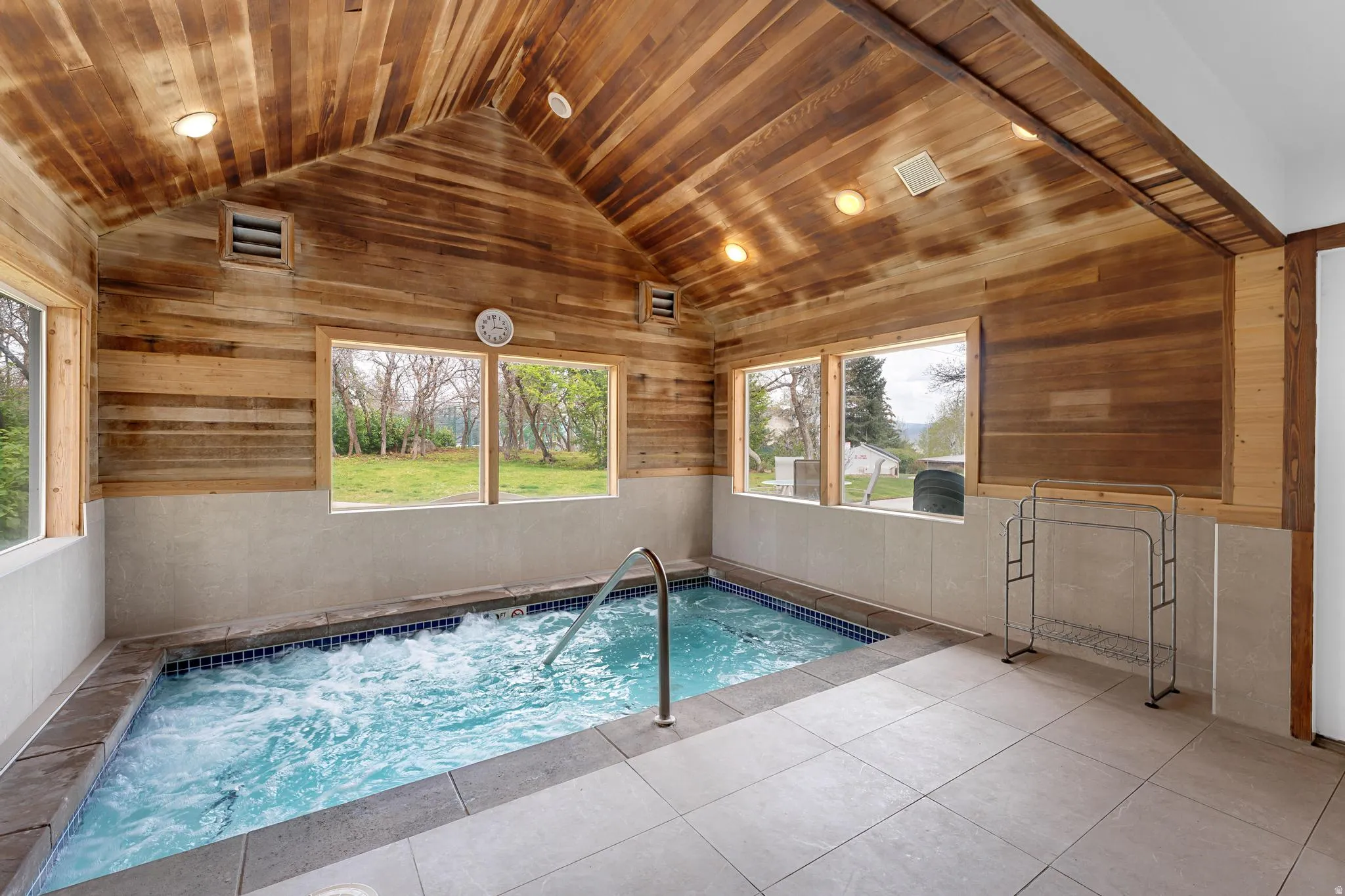 Indoor spa featuring a wood-paneled vaulted ceiling, integrated lighting, tiled flooring, and multiple windows