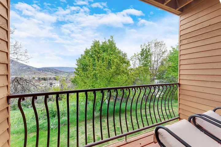 Wood-plank balcony featuring a decorative wrought iron railing, horizontal siding, and natural scenery