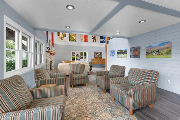 Spacious common area featuring shiplap walls, recessed lighting, wood-finish flooring, multiple windows, and a stone fireplace