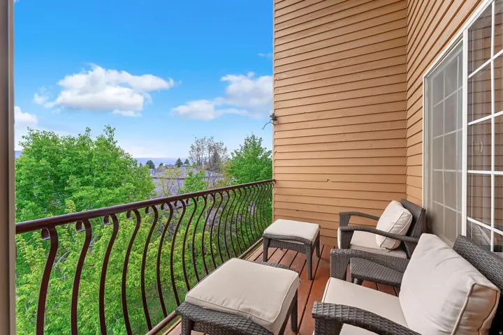 Balcony with wood-finish flooring, ornate metal railing, and horizontal wood siding