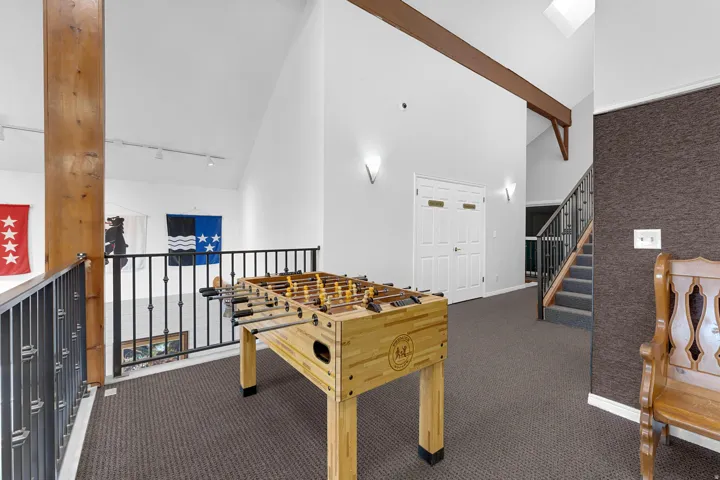 Upper-level landing featuring vaulted ceilings, a skylight, exposed wood beams, and carpeted flooring