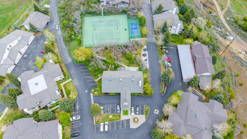 Community tennis courts, paved parking areas, multiple residential structures, and mature trees