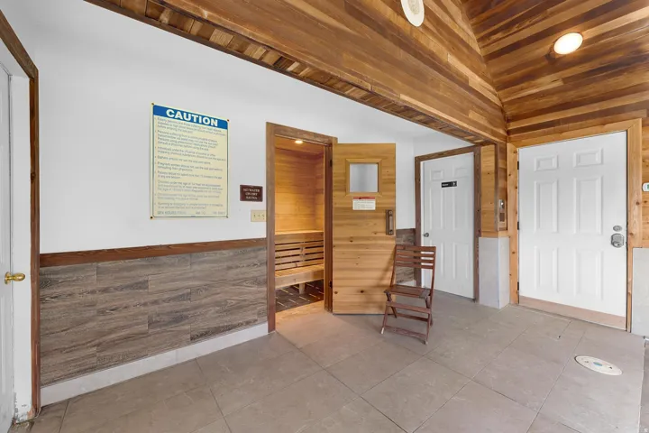 Sauna with wood-paneled interior, wood-finish flooring, and wood-paneled ceiling
