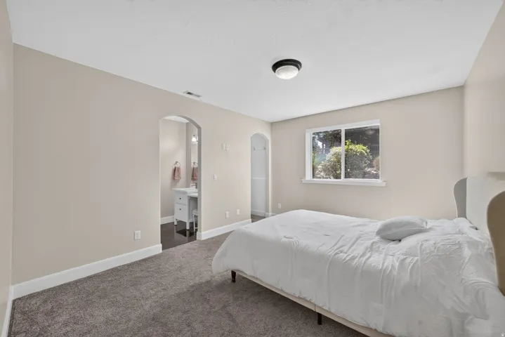Carpeted flooring, arched doorway, recessed window, flush-mount ceiling light