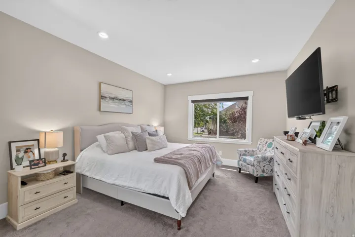 Recessed ceiling lighting, neutral wall tones, carpeted flooring, and a large window with white trim