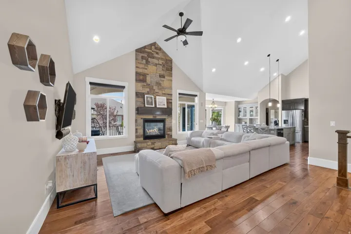 Vaulted ceilings, wood-finish flooring, stone-clad fireplace, integrated ceiling lighting, and stainless steel appliances