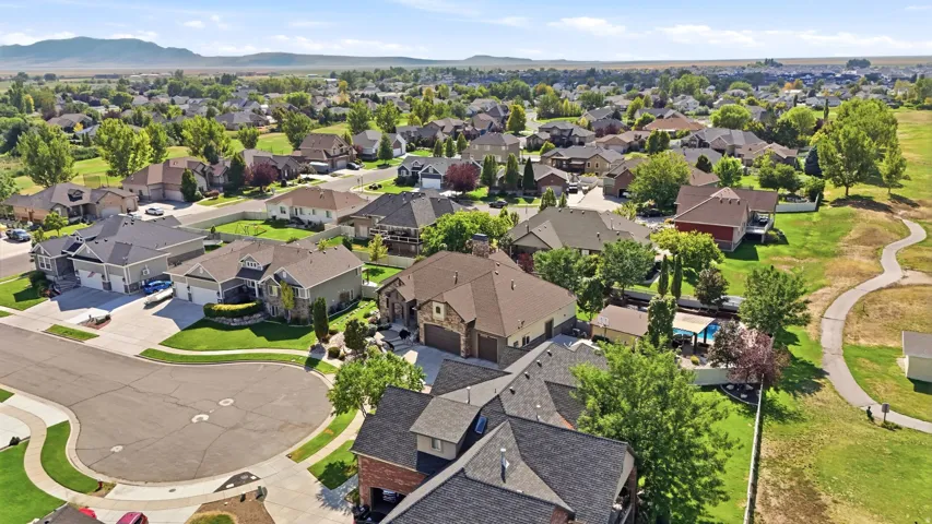Residential neighborhood with paved streets, mature trees, and mountain backdrop