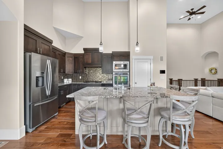 Kitchen featuring a central island with a stone-finish countertop, dark wood cabinetry, stainless steel appliances, and wood-finish flooring