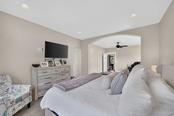 Recessed ceiling lighting, arched entryway, light gray wall paint, and ceiling fan