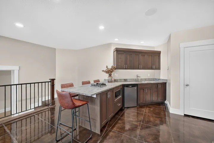 Built-in bar featuring wood-finish cabinetry, light-toned countertop, and stainless steel appliances