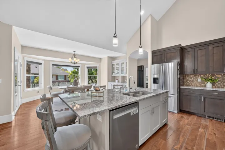 Gourmet kitchen with a large island, stainless steel appliances, wood-finish flooring, and a dining area with expansive windows