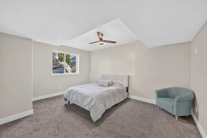Carpeted room with a window, ceiling fan, and neutral wall color