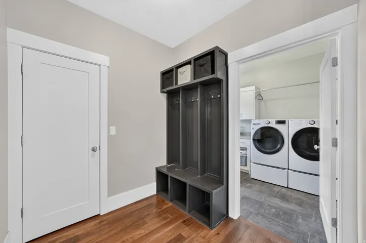 Hardwood-finish flooring, built-in storage bench with coat hooks, white panel interior doors, and a laundry area with tiled flooring