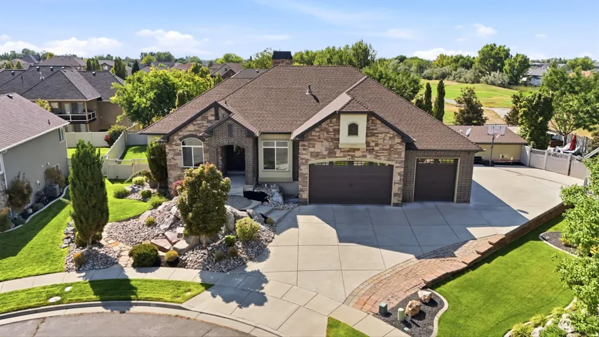 Stone and brick exterior with multi-pane windows, an attached two-car garage, and a concrete driveway