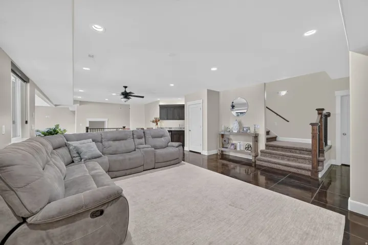 Recessed lighting, wood-finish flooring, dark wood-finish cabinetry, built-in ceiling fan, and staircase with carpeted treads
