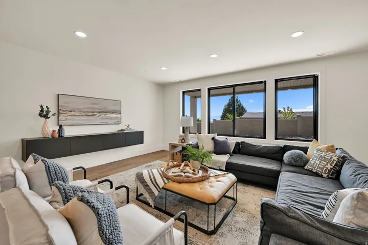 Recessed lighting, wood-finish flooring, a floating media console, and large windows with black frames