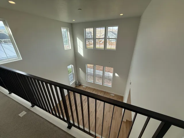 Two-story living area with multiple large windows, recessed ceiling lighting, and wood-finish flooring
