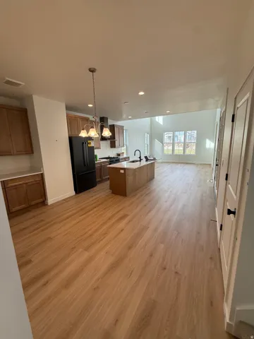 Open-concept living space featuring wood-finish flooring, recessed lighting, and a kitchen island with a built-in sink