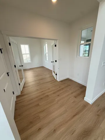Wood-finish flooring throughout, white walls, and bright white trim