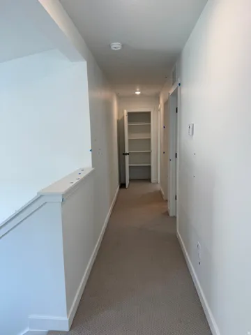 Hallway with light-colored carpeting and white walls