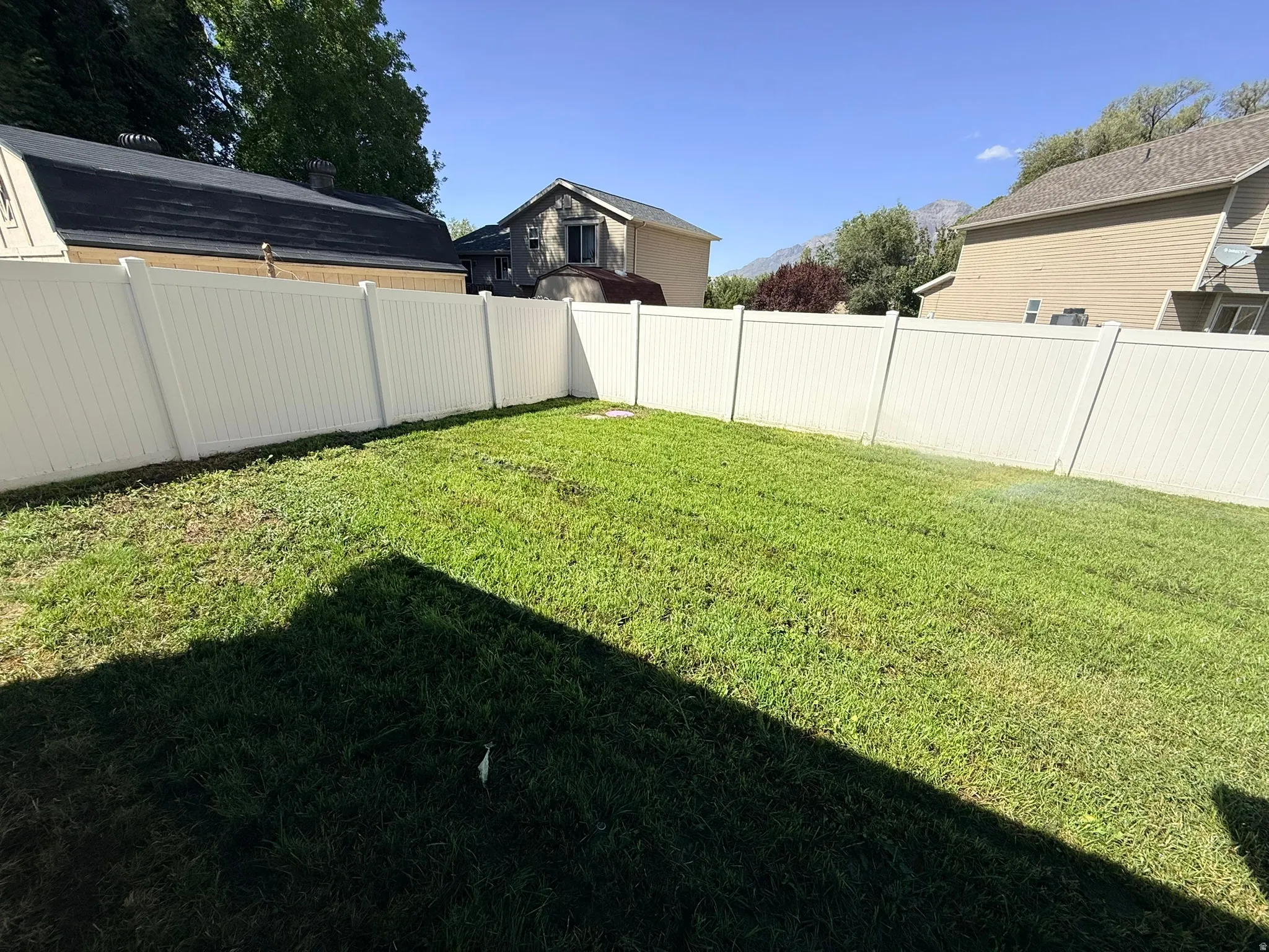 Expansive grassy area featuring a perimeter privacy fence