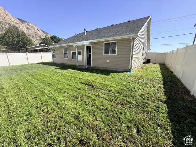 Expansive backyard featuring a manicured lawn, full vinyl privacy fencing, and a covered patio area