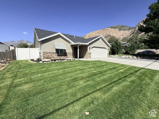 Well-maintained lawn with a paved driveway, a one-car garage, and a partial brick facade